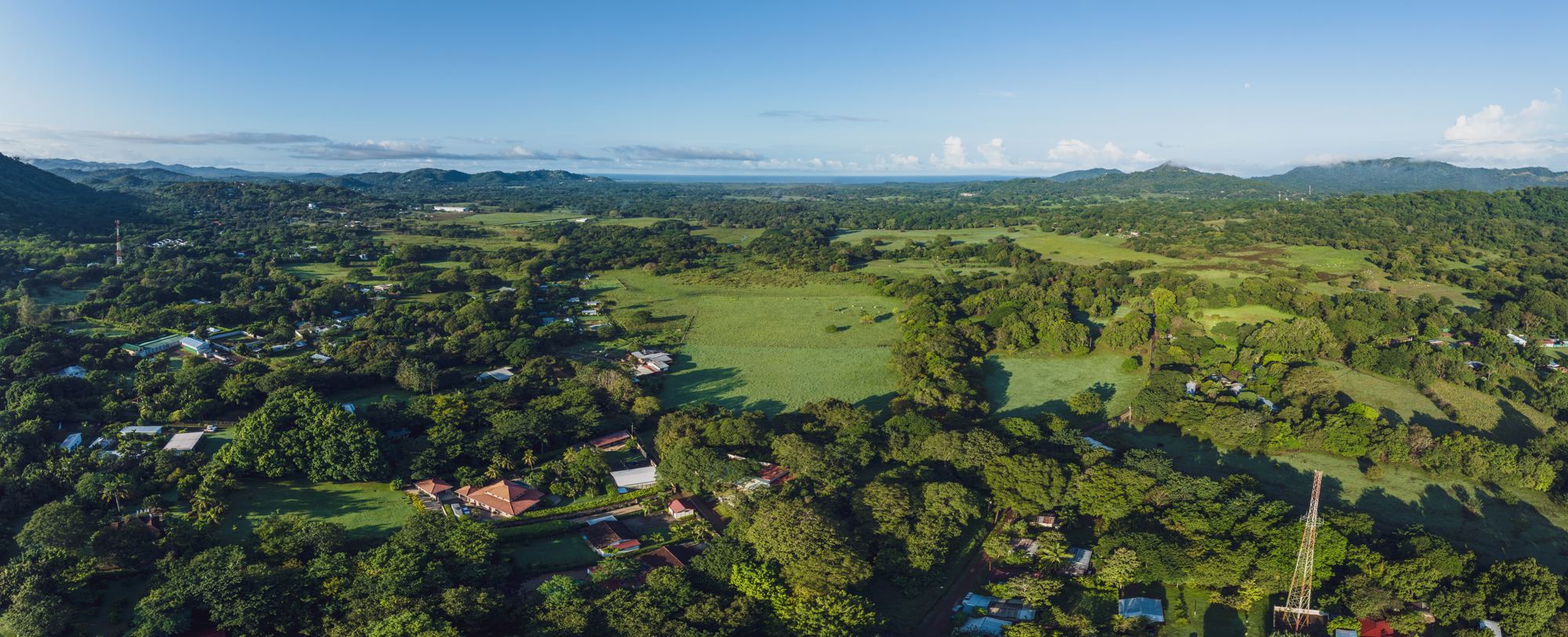 Real drone photo: the Guanacaste plains and the Pacific on the horizon, seen from above La Lomita